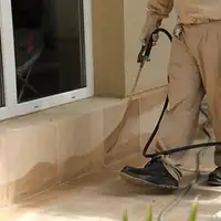 General pest control technician spraying exterior perimeter around a home in Gilbert, AZ